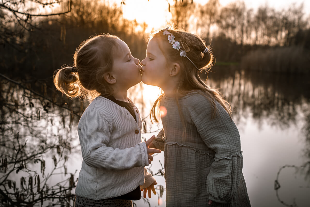zusjes kussen elkaar met zonsondergang
